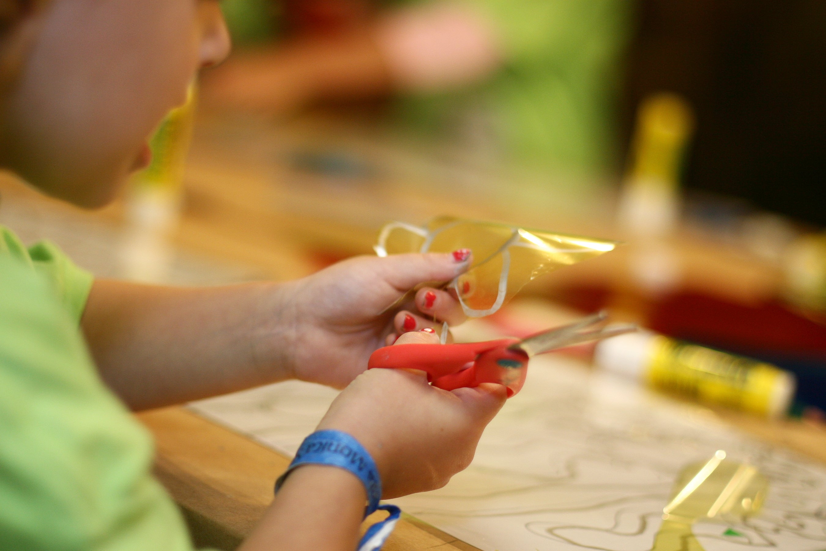 Child's hands cutting cellophane with scissors