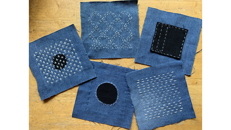 squares of blue fabric with white stitches