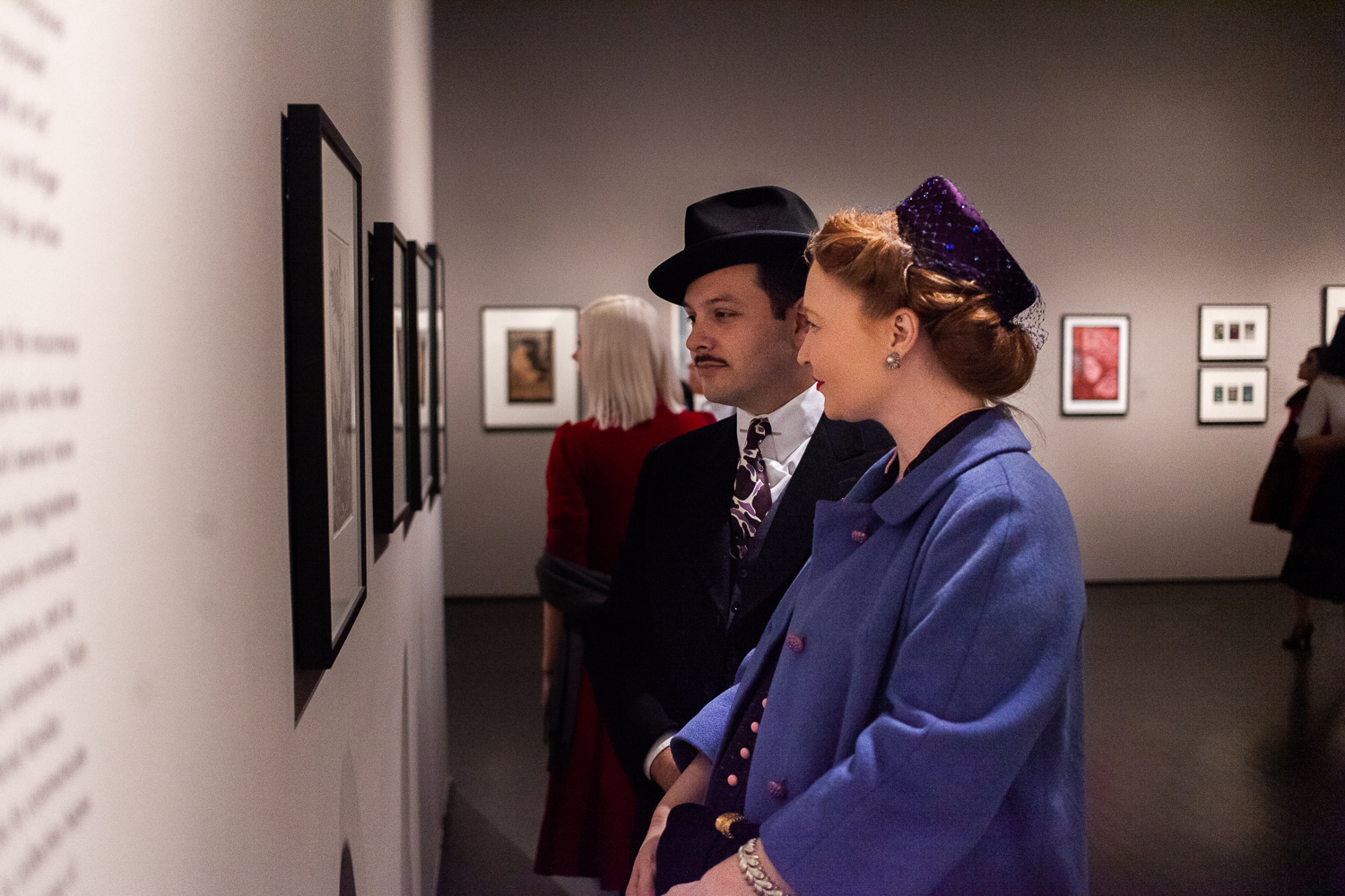 Two well-dressed people looking at art in a gallery.