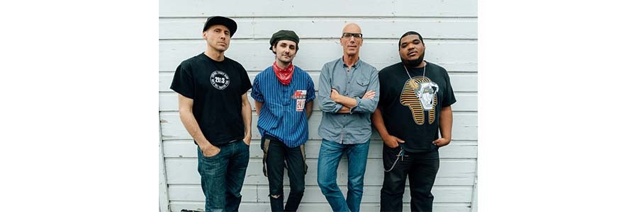 Image of the four members of the Zane Carney Quartet standing against a white wall