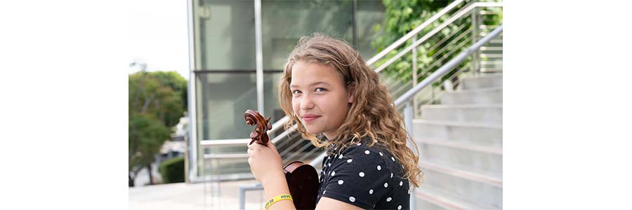Image of young blonde woman with curly hair, holding a violin 