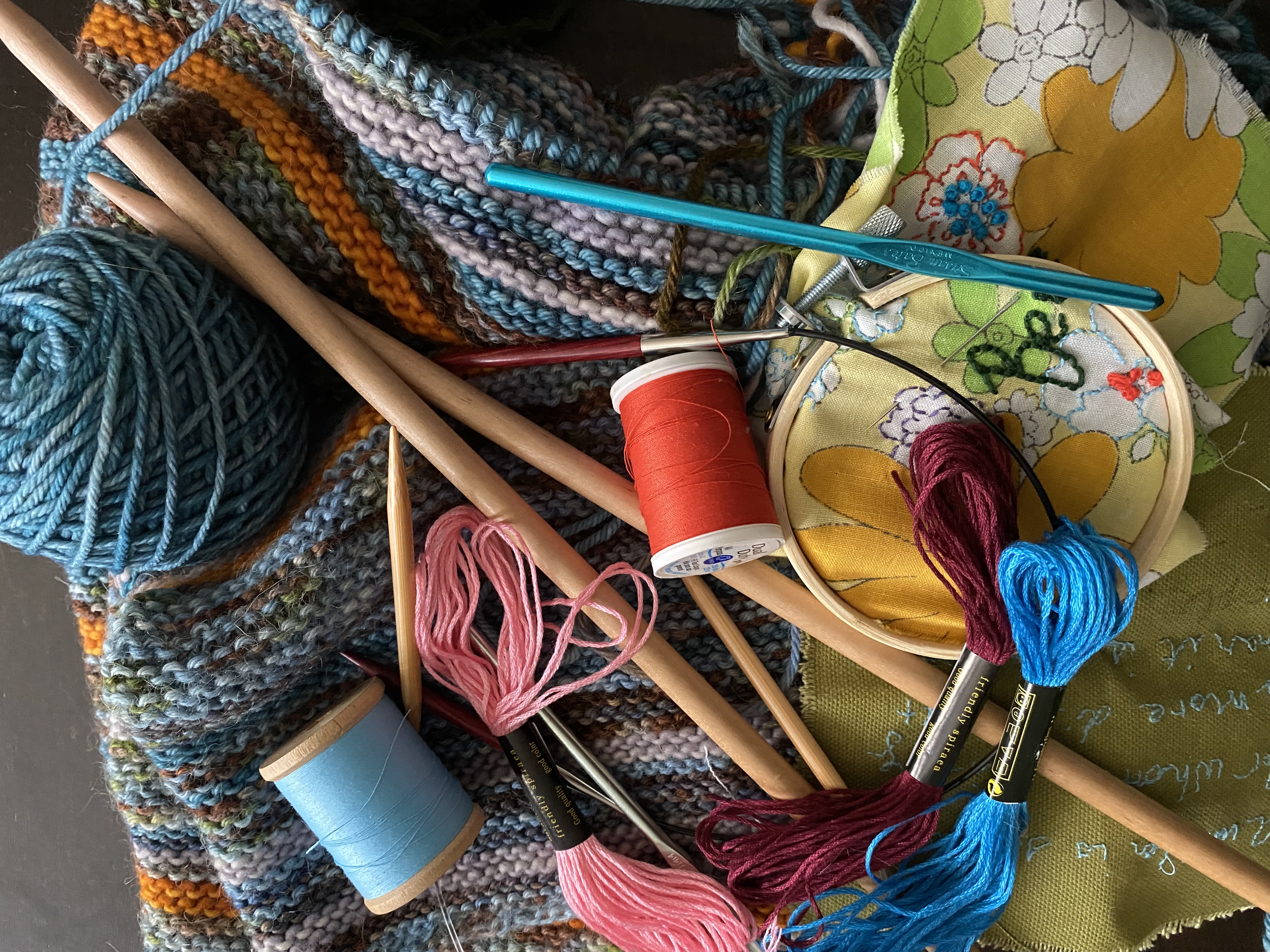 image of yarn, knitting needles, crochet hooks, spools of thread, embroidery thread and hoop, and knitting in progress. , and a  