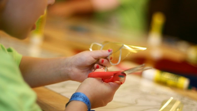 Child's hands cutting cellophane with scissors