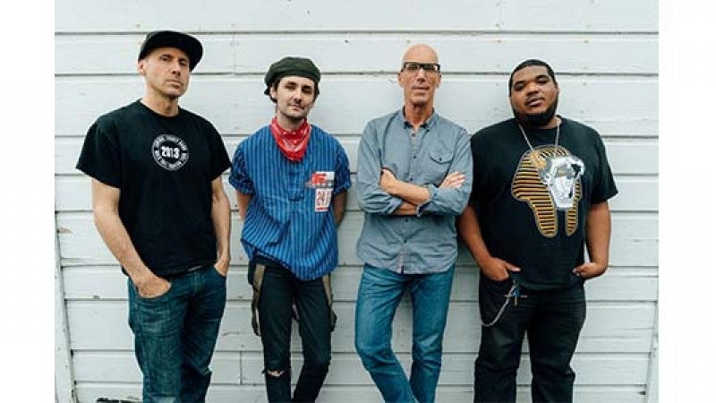 Image of the four members of the Zane Carney Quartet standing against a white wall