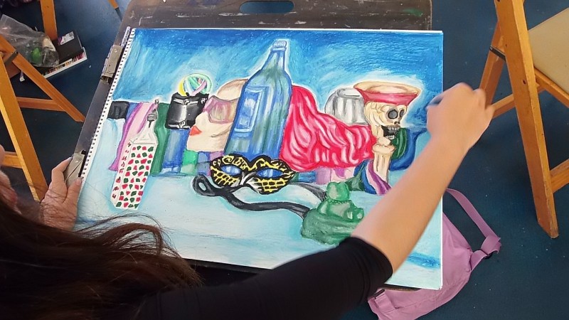 student working on pastel drawing of different vessels and forms