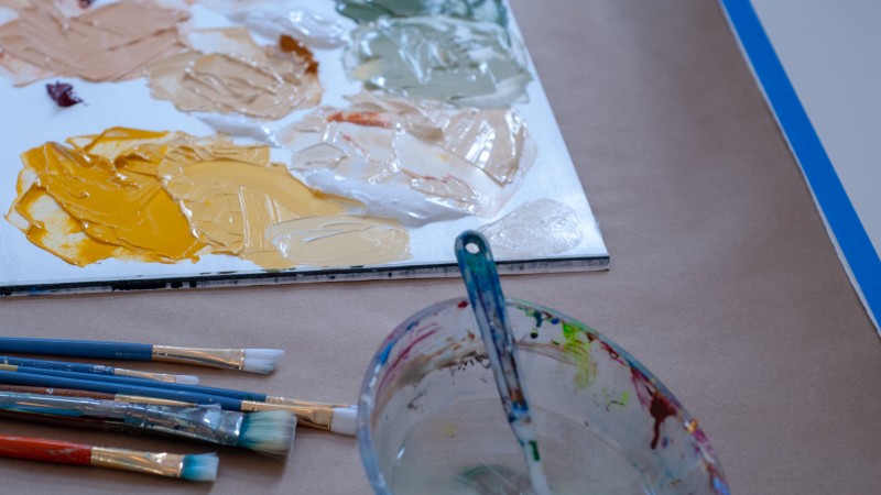arrangement of paintbrushes, a bowl of water, and a palette with paint