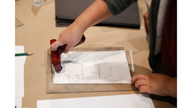 child using brayer to apply ink to foam printing plate