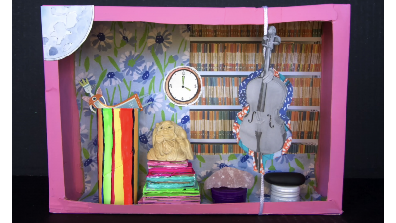 assemblage box with paper cut-outs, figures, stones, and bottle caps